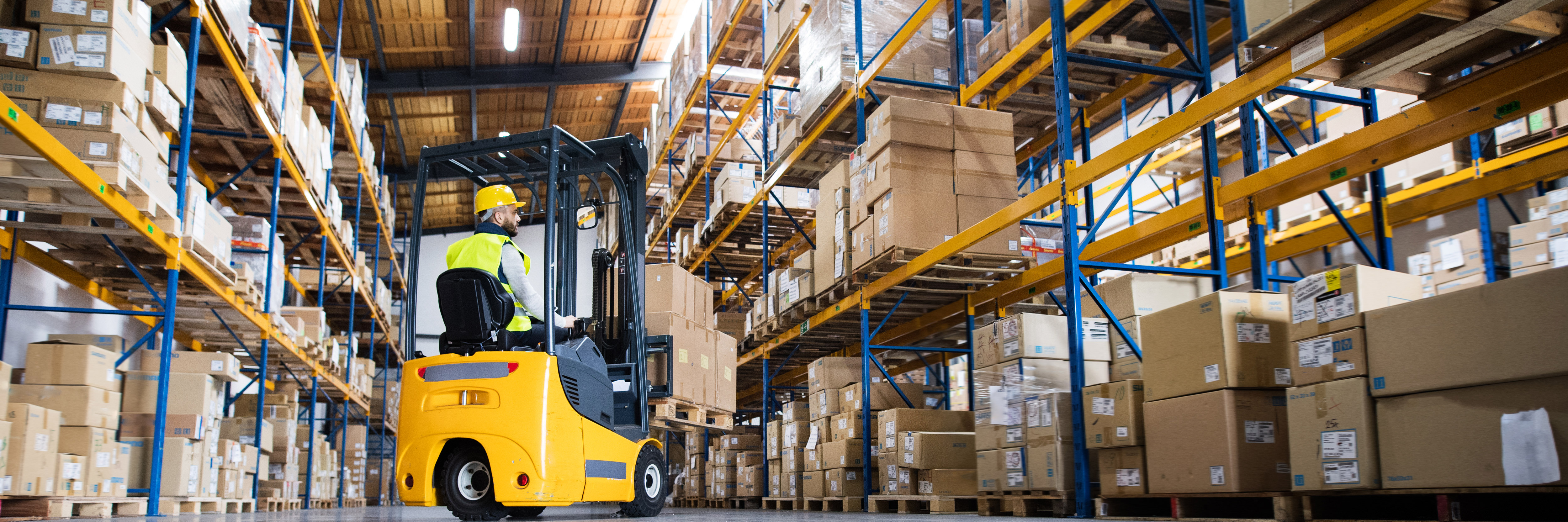 a forklift and operative in a warehouse aisle